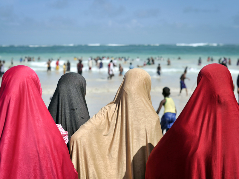Women dressed for Eid watch as hundreds of Somalis play at Lido beach in Mogadishu, Somalia. (Pic credit: United Nations Photo/Flickr)