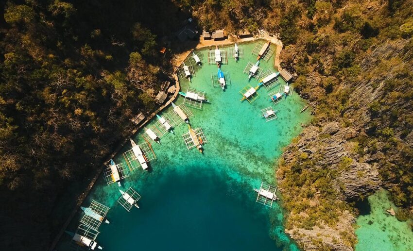 Aerial drone shot of the turquoise lagoon and jagged karst limestone cliffs at Kayangan Lake in Coron, Palawan, Philippines.