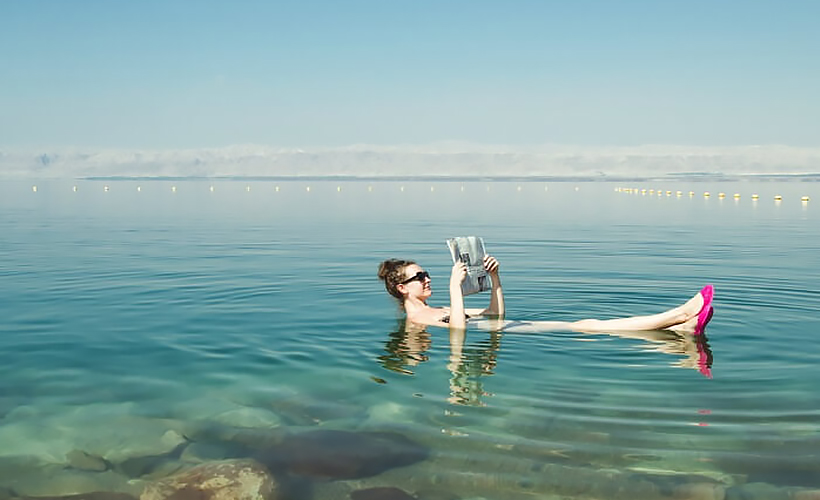 _A-woman-reading-newspaper-while-floating-on-the-waters-of-Dead-Sea-ss25072017