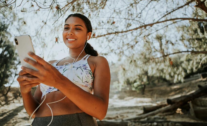 Woman wearing earphones standing outdoors during an early morning or evening workout session
