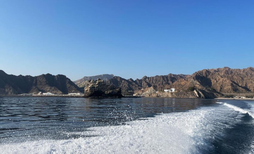 Boat wake in the clear turquoise sea of the Gulf of Oman, heading toward the Dimaniyat Islands' hidden gem.