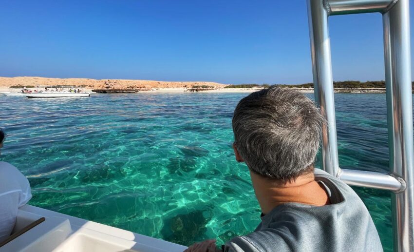 A man looking at the turquoise water of the Dimaniyat Islands near Muscat, Oman, during a snorkelling boat tour.
