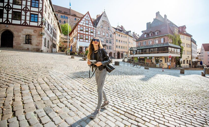 Female tourist sightseeing in a sunny European town square during a high-energy morning.