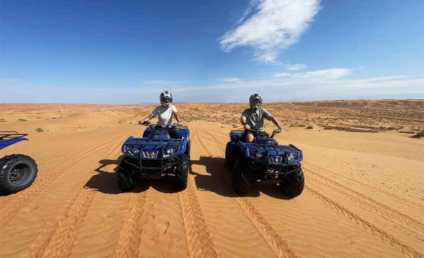 Sofia and her partner on dune buggies in the golden Wahiba Sands desert, showing adventure things to do in Oman.