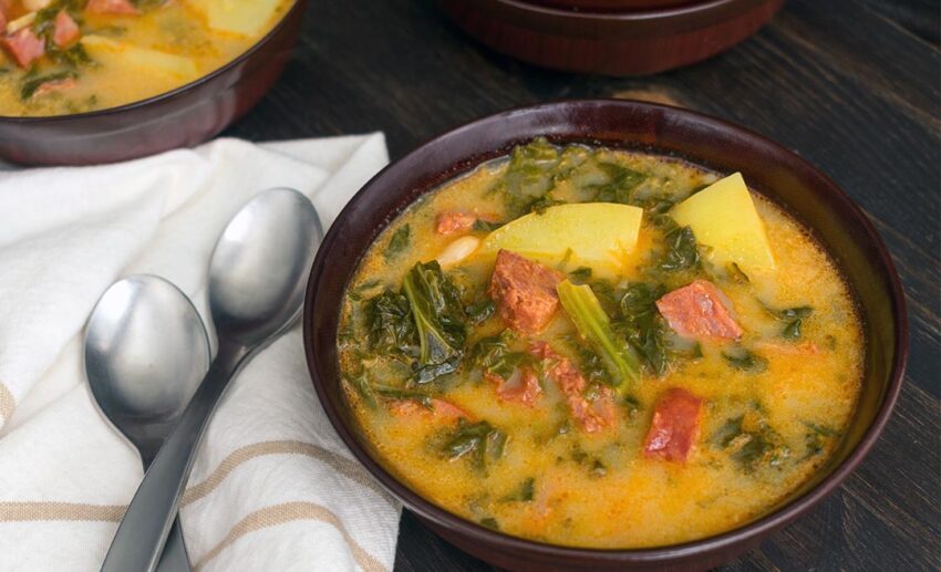 A bowl of Caldo Verde soup with kale, potato, and slices of chouriço sausage.