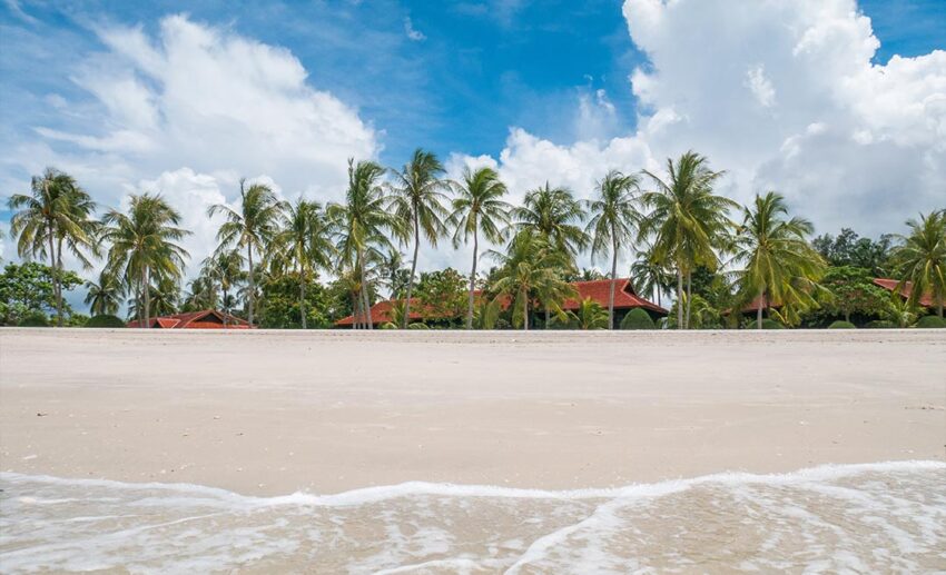 Pristine white sand beach and tropical coconut trees at a luxury resort in Langkawi, Malaysia.