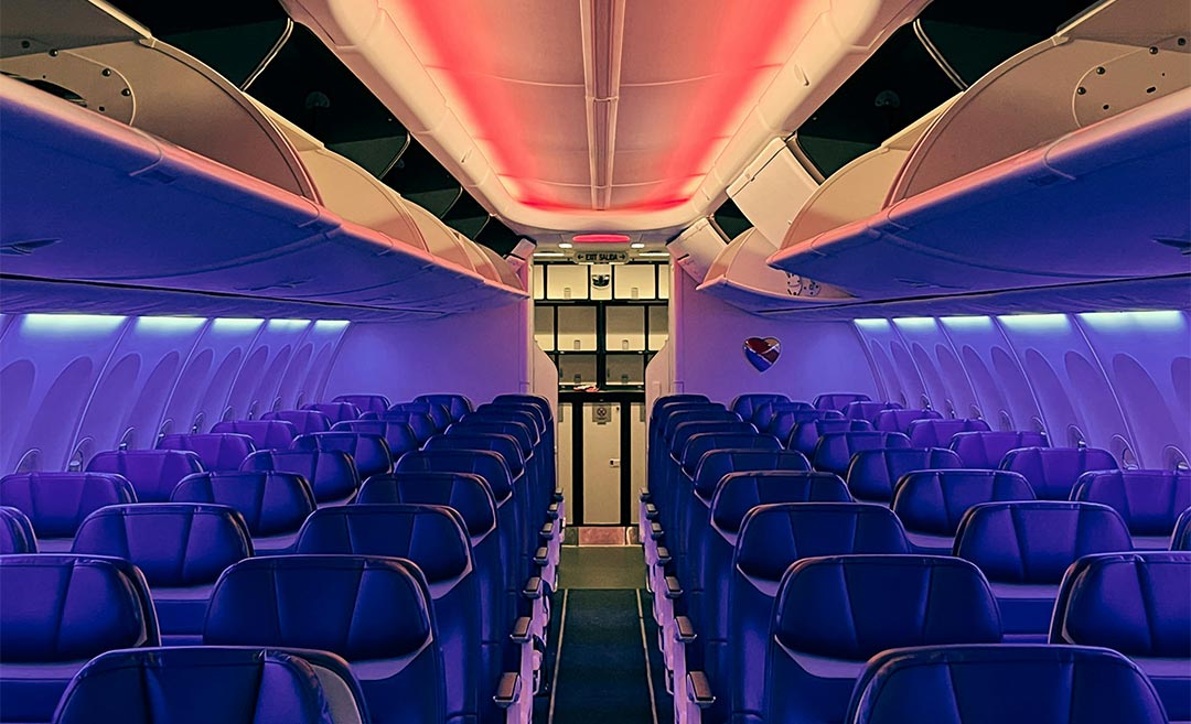Empty airplane cabin interior with overhead bins lit up at night, highlighting in-flight security.