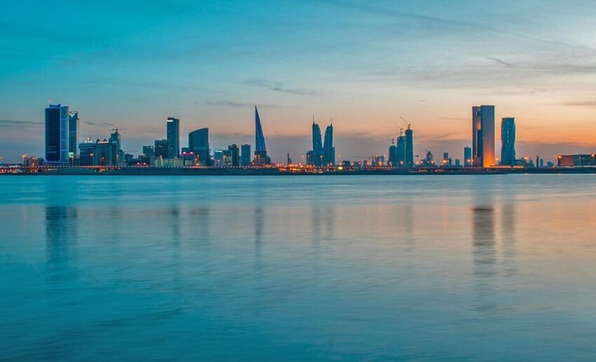 Sunset view of the Manama, Bahrain city skyline and skyscrapers reflected over the Persian Gulf waters.