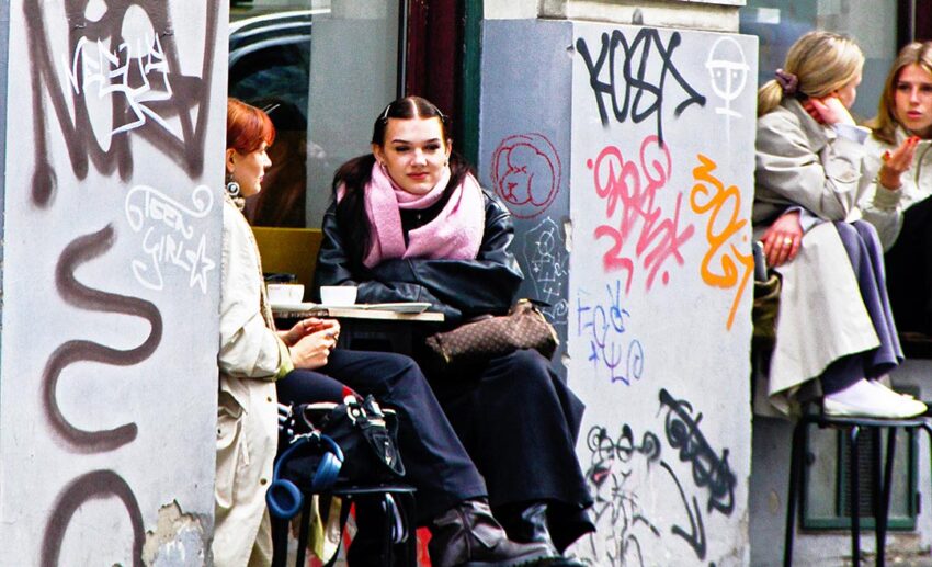 Women seated at outdoor tables in Vienna's Spittelberg district, surrounded by artistic graffiti and a bohemian student atmosphere.