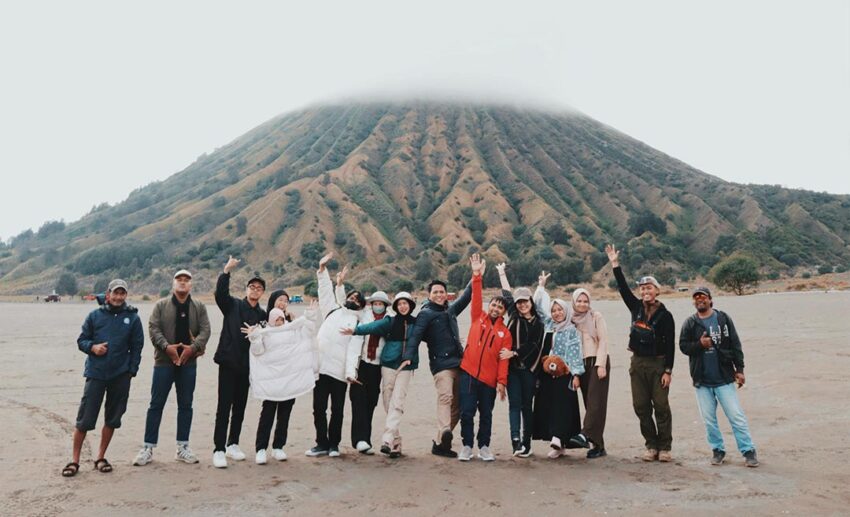 A group of traveller friends standing on a vast sandy beach in Malang, Indonesia, enjoying a domestic group getaway.