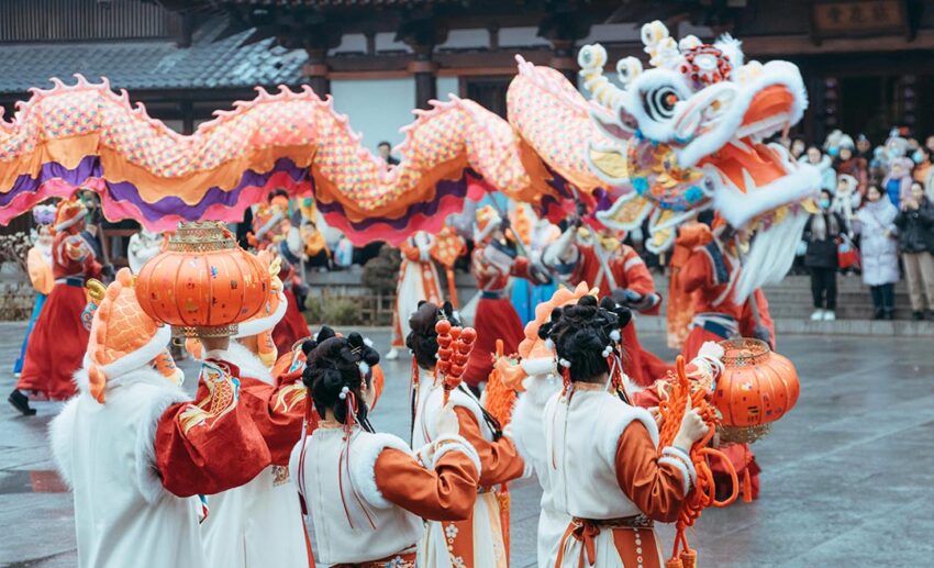 Performers holding a long, colourful dragon and lanterns during an outdoor Dragon Dance Festival parade.
