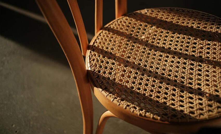 Close-up of a handcrafted rattan chair featuring an intricate woven seat pattern, highlighting traditional Malaysian furniture design.