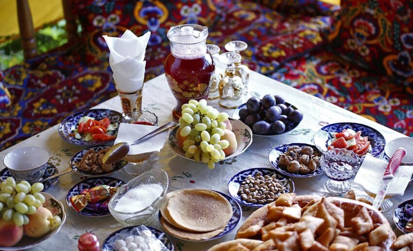 A traditional Kyrgyz tea spread featuring fresh fruits, local desserts, snacks, and tea served in a cultural setting.