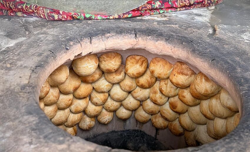 Traditional meat-filled samsas baking inside a clay tandoor oven, a popular street food in Kyrgyzstan.