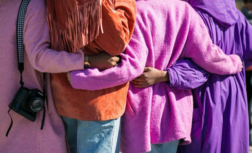 A back view of four women side-hugging each other at the waist.