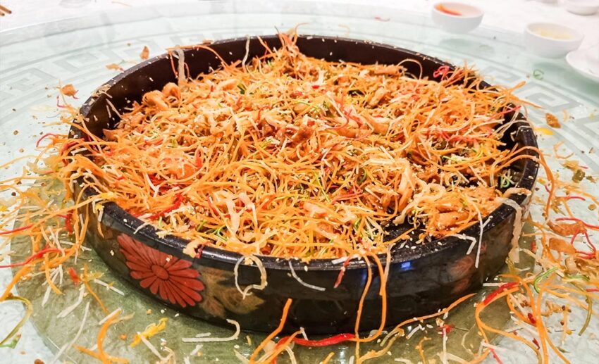 The aftermath of a Yee Sang prosperity toss showing scattered ingredients across a table, symbolising an abundance of good luck and fortune.