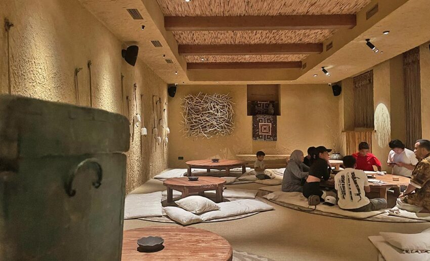 The interior of Yurta restaurant in Almaty showing a traditional nomadic dining area with floor seating, low tables, and ethnic textiles.