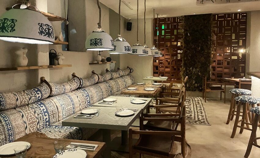 A modern dining section inside Yurta restaurant with elegant wooden tables, contemporary chairs, and subtle nomadic decor.