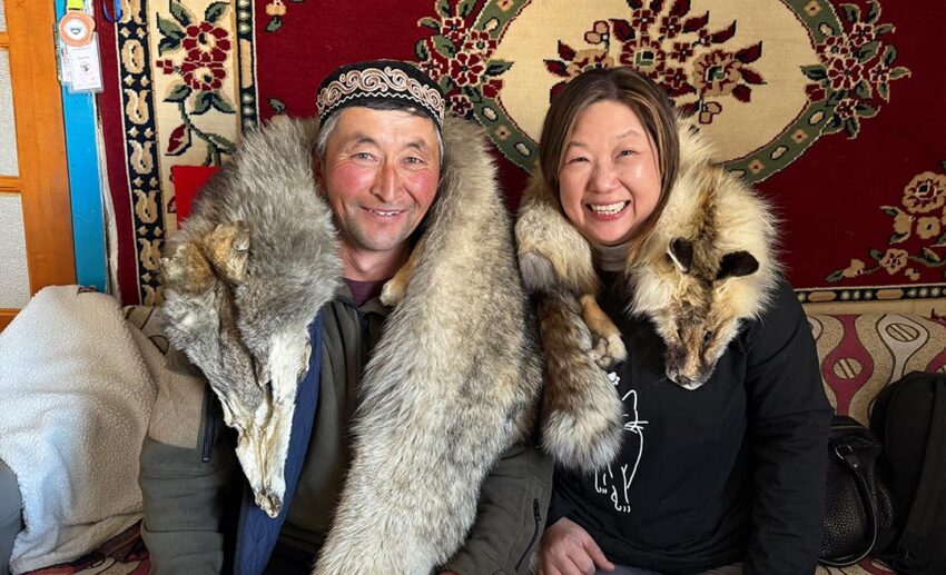 Solo female traveller Lynette Yee sitting and conversing with an eagle hunter inside his traditional decorated ger in western Mongolia.