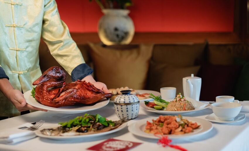A traditional Chinese New Year reunion meal featuring roast duck and various celebratory dishes symbolising abundance.