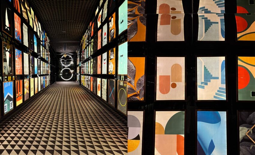 A perspective shot of the entrance walkway to JIN Gastrobar, with dark geometric ceilings and walls lined with lit-up abstract posters and patterns.