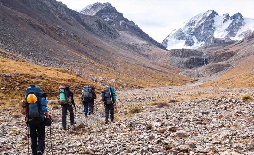 A group of hikers trekking through the rugged and expansive Tian Shan mountain range in Kyrgyzstan.