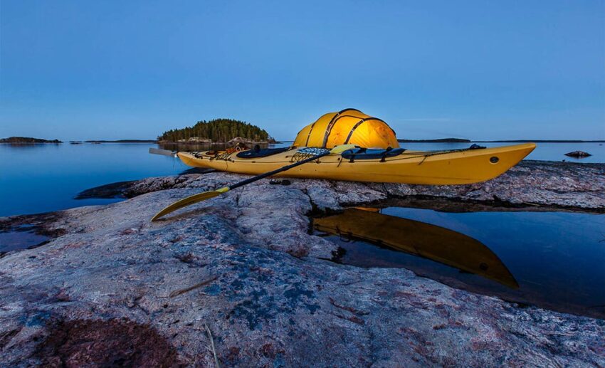 A bright yellow canoe parked on the shore of Lake Saimaa, Finland, highlighting summer outdoor activities in the Lakeland region.