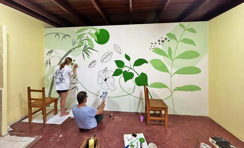 A collaborative moment of creativity: the writer and her friend painting a colourful, detailed mural on a school wall in Liberia to leave a lasting mark on the community.