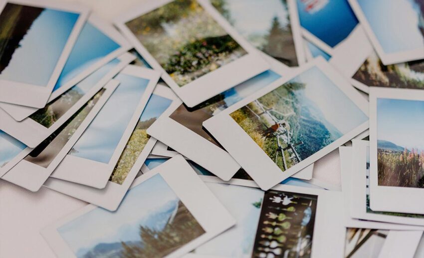 A scattered pile of instant film Polaroid photographs on a table, representing the results and milestones of a productive creative retreat.