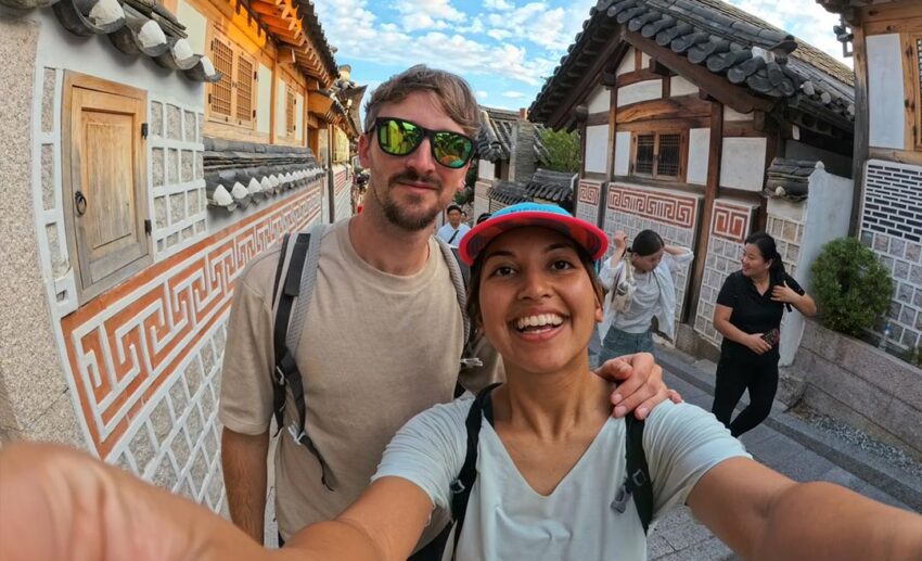 A selfie (wefie) of the writer and her partner smiling on a traditional street lined with hanok houses in Bukchon Hanok Village, Seoul.