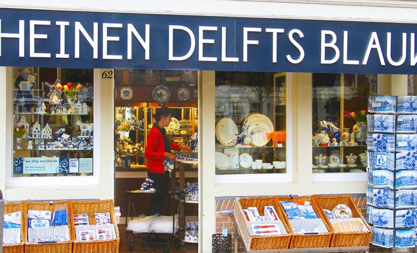 The storefront of a Heinen Delft Blauw boutique, displaying a vibrant array of traditional blue and white Dutch ceramics and hand-painted souvenirs.