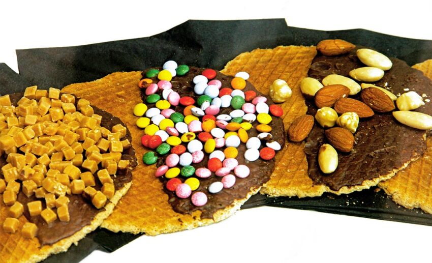 A close-up of a golden-brown Dutch stroopwafel, a traditional syrup-filled waffle biscuit found in the local bakeries of Delft.
