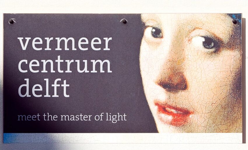 The exterior signage of the Vermeer Centrum Delft, featuring an iconic close-up of the Girl with a Pearl Earring, the city’s most famous artistic legacy.