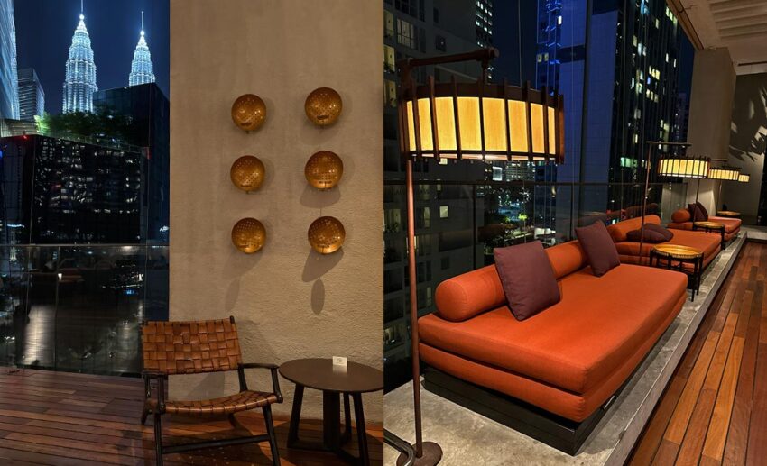 Wide shot of SANTAI lounge under a deep blue twilight sky with the illuminated Petronas Twin Towers in the background.