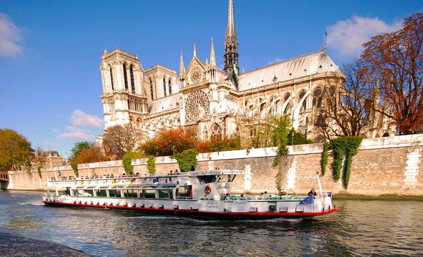 A river cruise boat on the Seine in Paris with the Notre-Dame de Paris cathedral in the background.