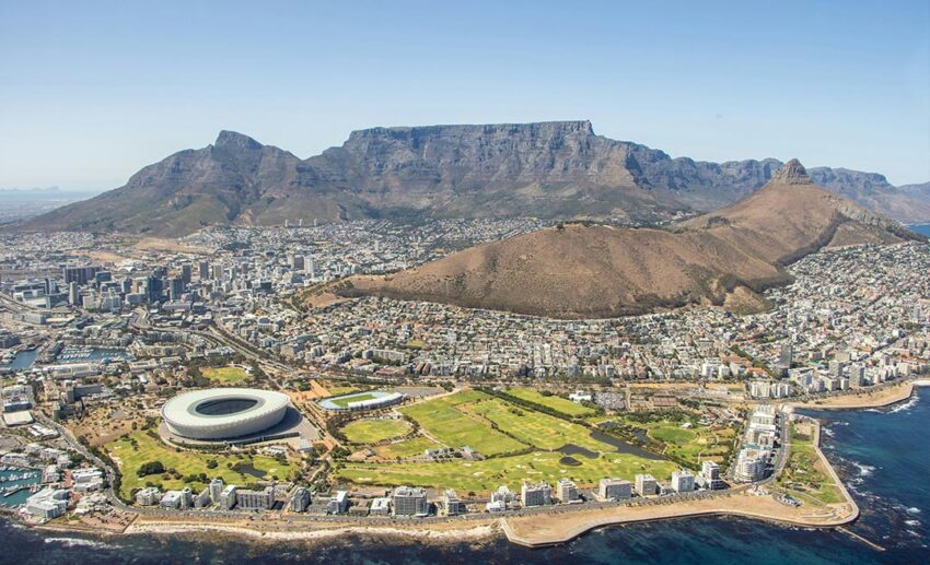 An aerial view of Cape Town, South Africa, nestled between the blue ocean and the iconic flat-topped Table Mountain.