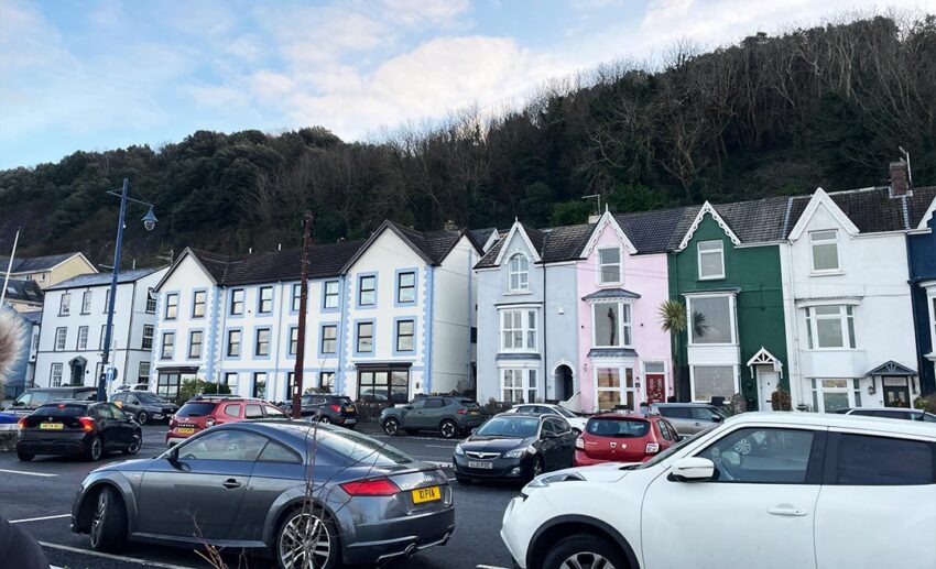 A row of elegant, colourful seaside houses and bungalows along the coast in Mumbles, Wales.
