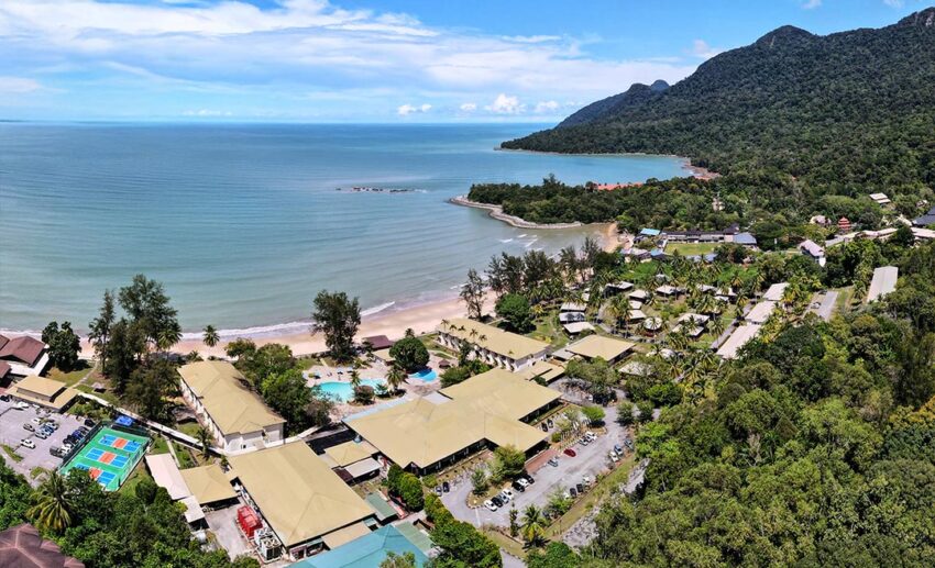An aerial view of Damai Beach Resort in Santubong, Sarawak, showing the hotel buildings nestled between lush green mountains and the South China Sea.