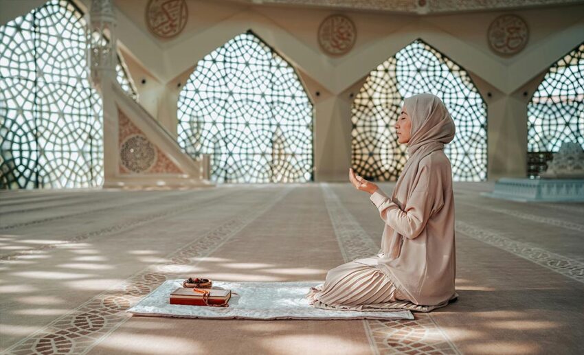 A woman praying peacefully inside a mosque, capturing a moment of spiritual connection while travelling.