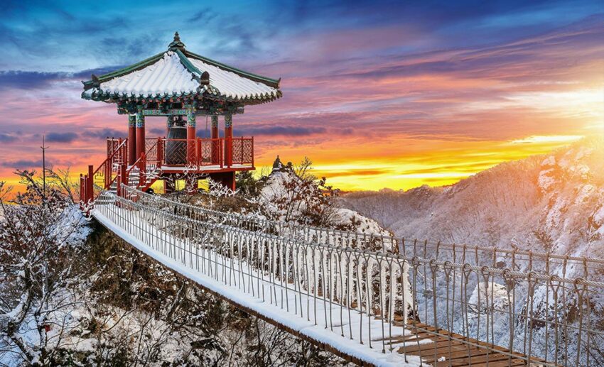 The traditional YakSaam Temple at sunset, situated within the snowy Geumosan Mountains of South Korea during winter.