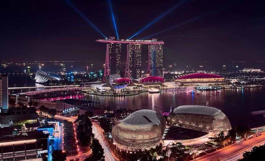 The modern high-rise skyline and cityscape of Singapore illuminated by lights at night.