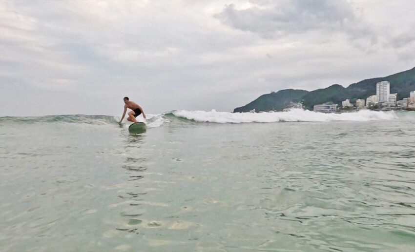 A surfer riding a wave at Songjeong Beach in Busan, a popular spot for slow travel and surfing in South Korea.