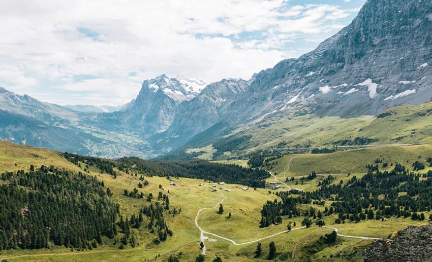 A scenic daytime view of the Swiss Alps with lush green trees and mountains near Wengen and Lauterbrunnen, Switzerland.