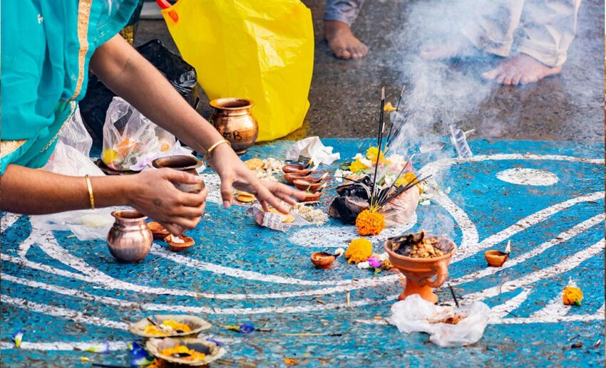 A colourful Hindu ritual ceremony taking place at a Ganga Ghat in Kolkata, India, showing devotees and traditional offerings by the river.