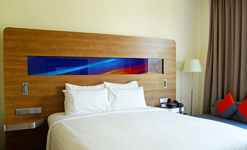 A modern and comfortable guest room interior at the Novotel Taiping hotel, featuring views of the surrounding hills.
