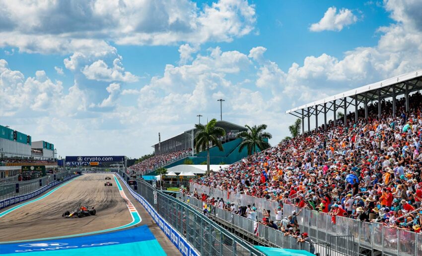 A red Red Bull Formula 1 car navigating a turn at the Miami Grand Prix with full spectator stands in the background.