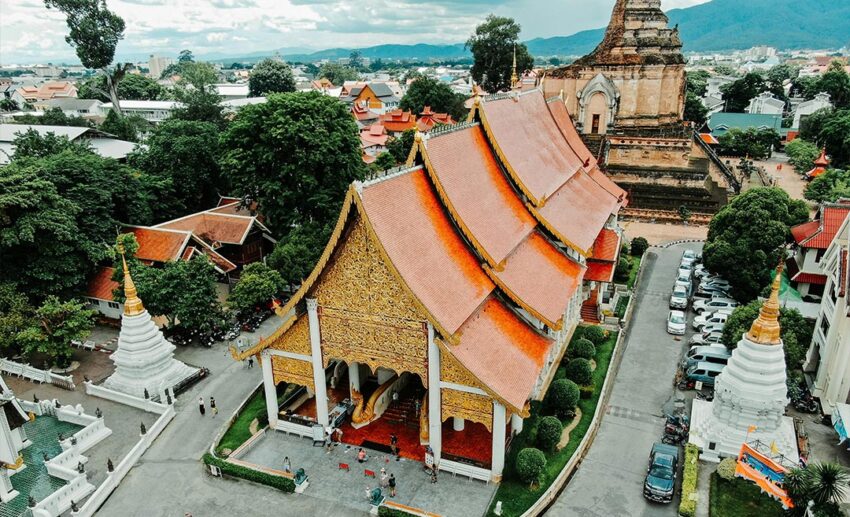 The historic and majestic stone facade of Wat Chedi Luang temple against a soft sky in Chiang Mai.