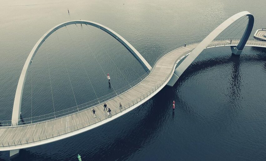 An aerial view of the winding Elizabeth Quay Bridge over the Swan River in Perth, showcasing modern architectural design and water.