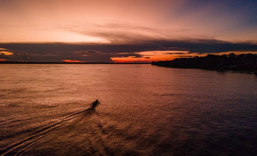 A serene sunset over the Amazon River in Leticia, Colombia, with vibrant colours reflecting on the tranquil water.