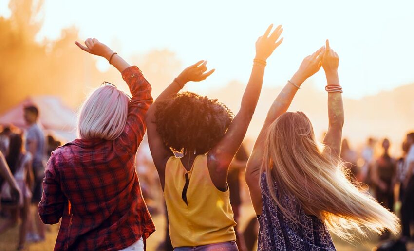 Multiethnic women celebrating and dancing together at an outdoor music festival or live concert.